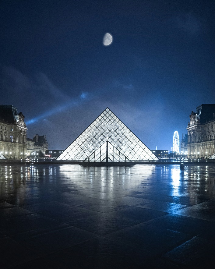 Image of the Louvre Museum's glass pyramid at night, lit up inside