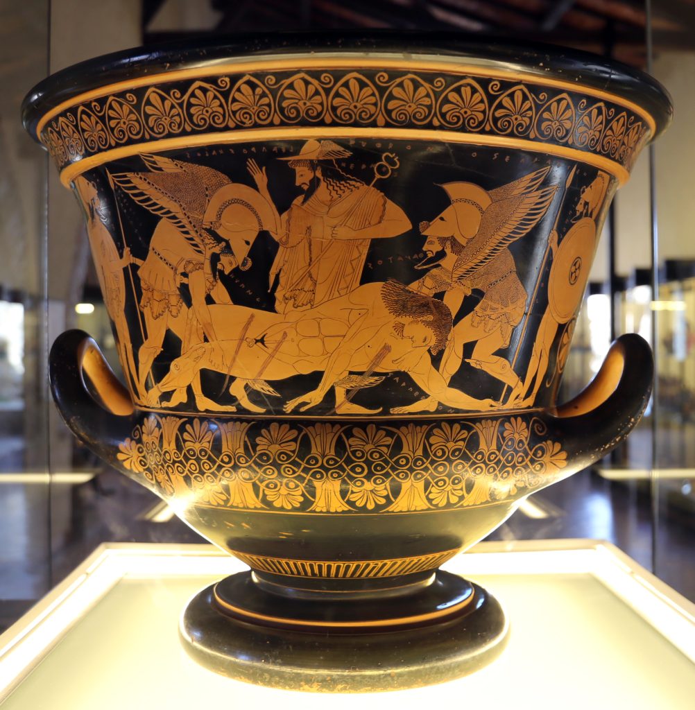 A photo of an ancient Greek krater attributed to Eufronios, depicting the death of Sarpedon. The vase, dated between 520-510 BCE, features intricate red-figure painting that illustrates Sarpedon, a heroic figure from mythology, lying on the ground with warriors around him.