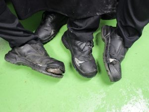 Workers with black pants and worn out black shoes are contrasted with a lime green floor.
