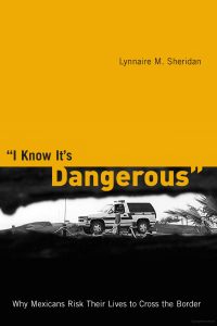 Cover of book "I know it's dangerous". The image is looking through the US border wall towards a Border Patrol vehicle.