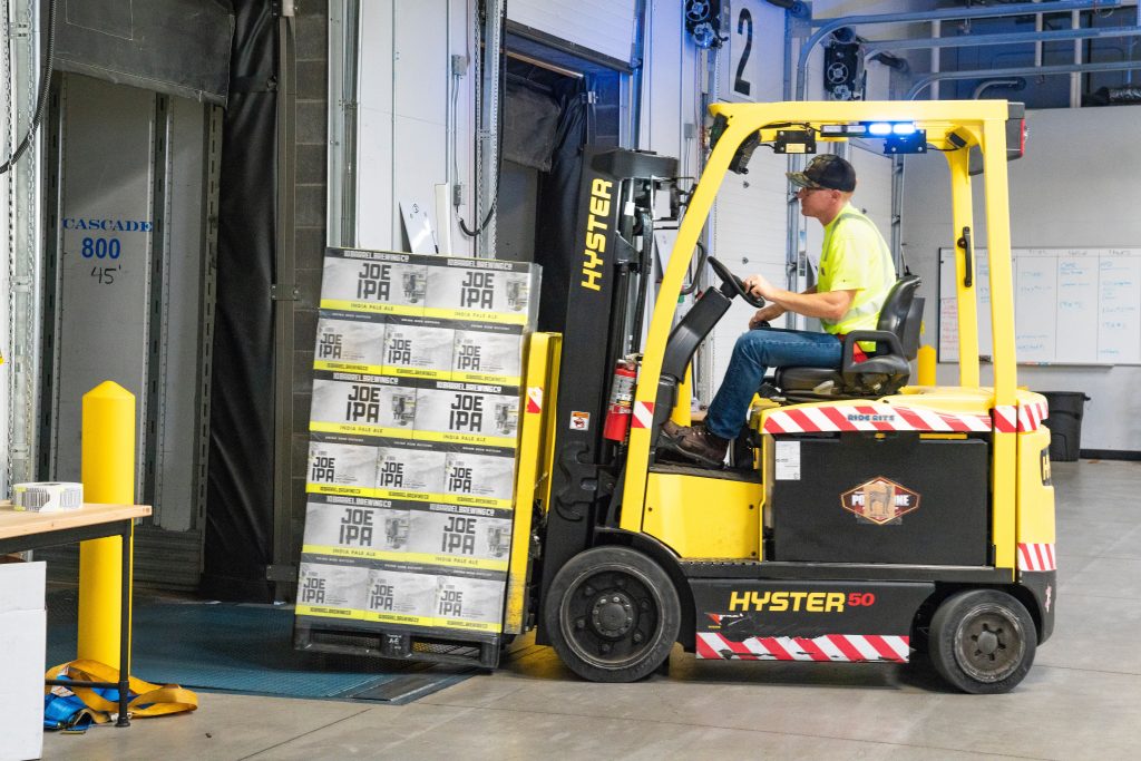 A forklift truck is being used to load boxes of Joe IPA into what may be a commercial cool room.