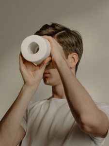 A young man looking through a toilet roll as if it were a telescope