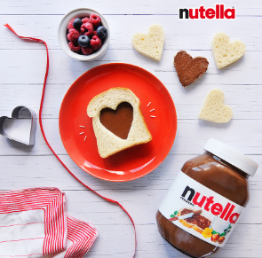 Nutella advert with heart-shaped cookie cutter and berries with white bread on a red plate