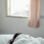 Woman lying in bed under an open window
