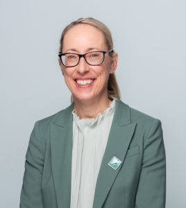 Image of Michelle Gander with blonde hair tied back and a green blouse and jacket