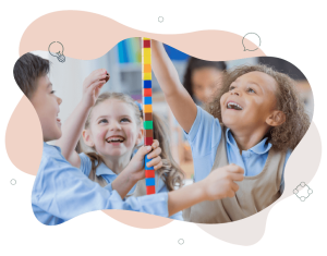 Children laughing and building a tower of bricks as tall as they can get