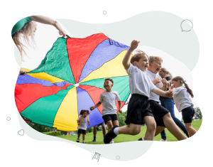 Children laughing and having fun running under a rainbow parachute held by the teachers.