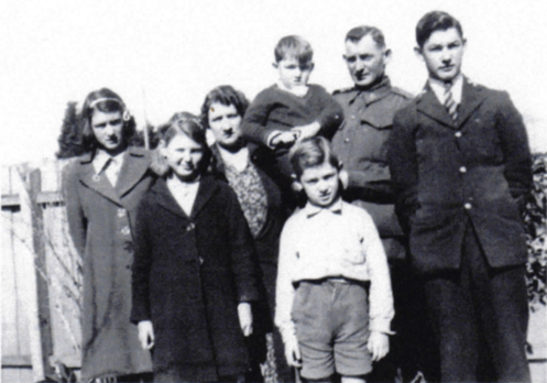 Black and white group family photo depicting Jessie Aileen, Muriel (Jim's wife), Jim (holding Graeme), William (in front) Harold.