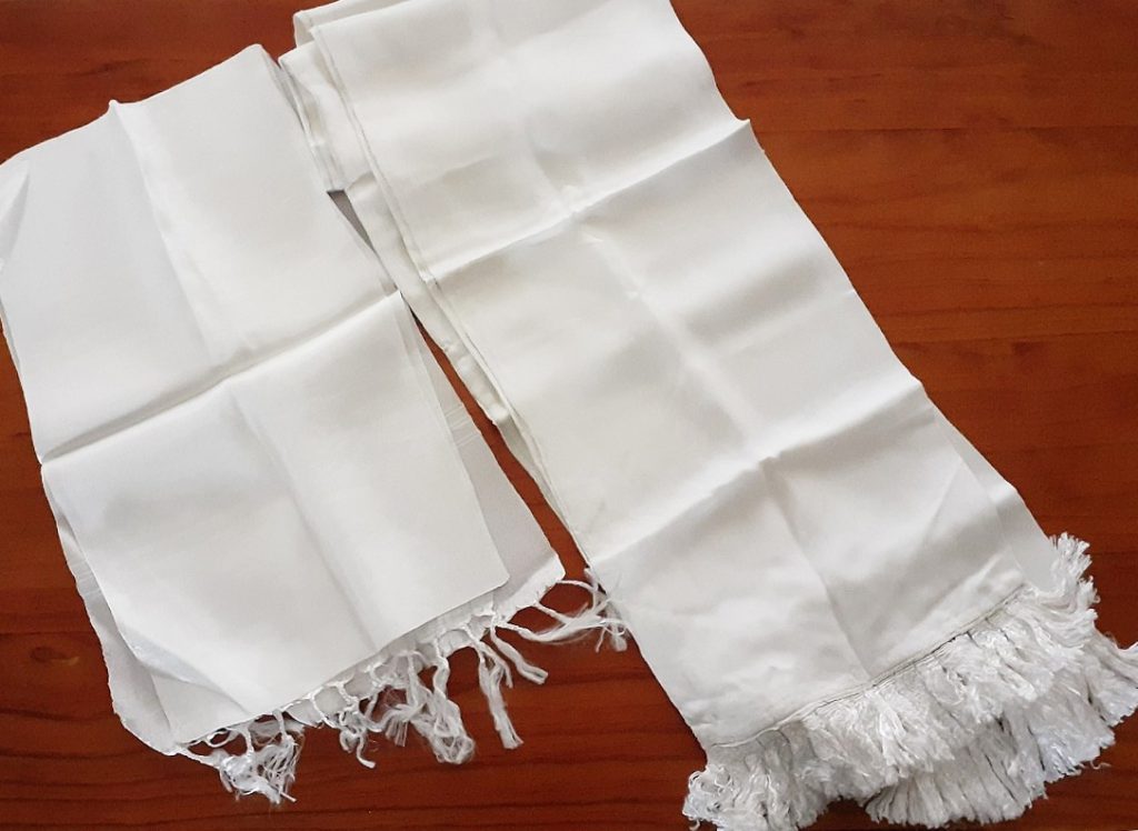 Photo of two white silk scarves neatly folded on a table.
