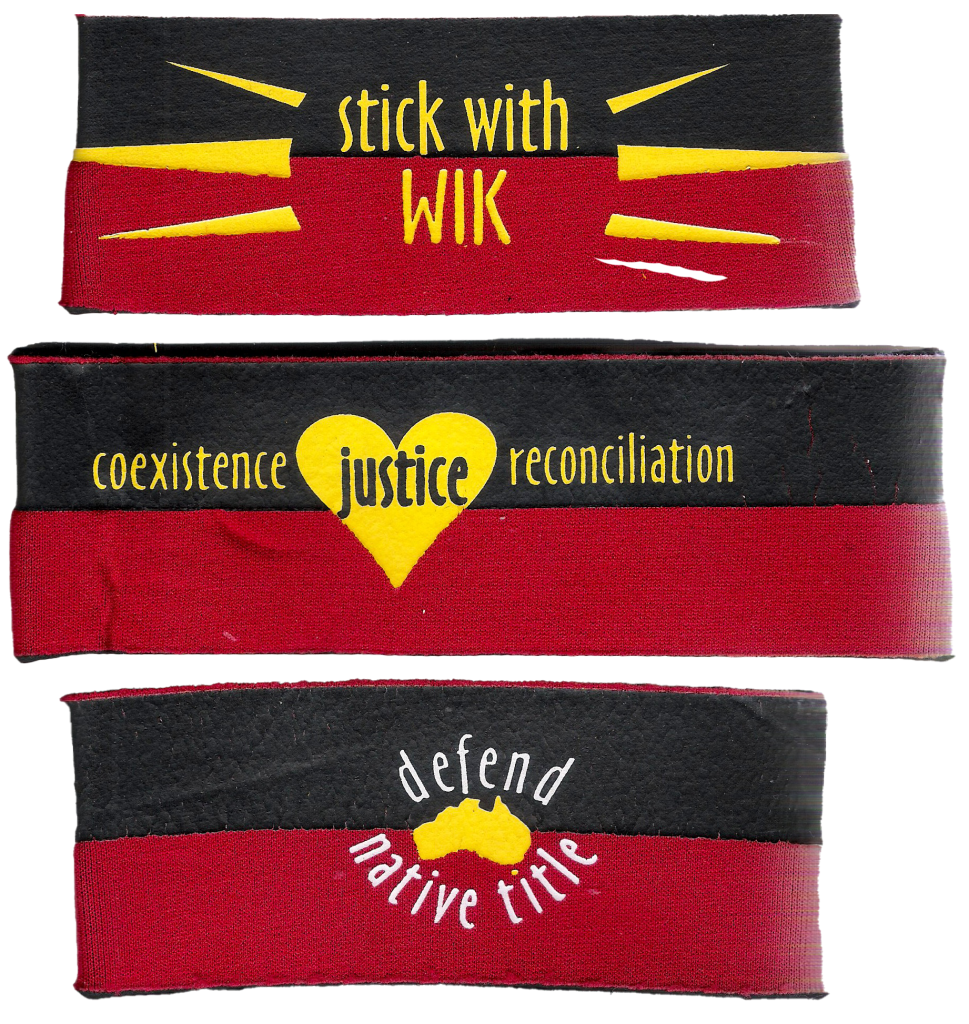Scanned image of 'Stick with Wik' armband in black, red and yellow colours. In yellow, words read: 'coexistence', 'justice', 'reconciliation', and 'defend native title'.