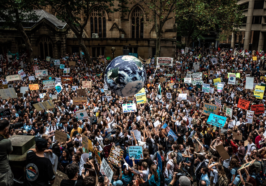 Colour photograph of a large peaceful protest on the streets of Melbourne, Australia. in the middle of the frame is a large inflatable earth that is held up by the protesters.